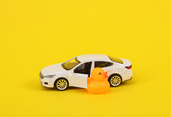 Rubber duck with a car on a yellow background. Driving concept