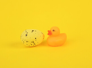 Rubber duck with easter egg on yellow background