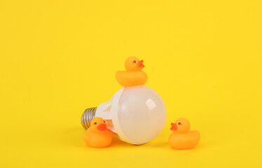 Ducklings with a light bulb on a yellow background. Fresh idea