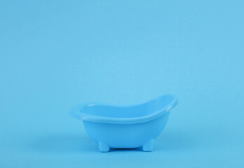 Miniature plastic bath on a blue background