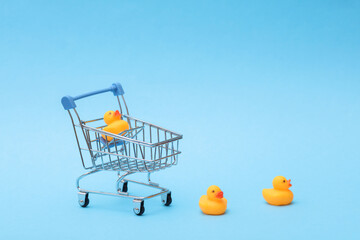 Rubber ducks with shopping trolley on blue background. Ninimalism creative layout