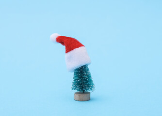 Miniature Christmas tree in a santa hat on a blue background