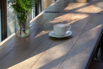 Close up photo of hot coffee on wooden table. Light and shadow.