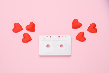 White audio cassette with hearts on pink background. Romantic music, love, valentine's day concept