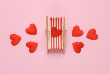 Deck chair with hearts on pink background. Romantic holiday, love concept