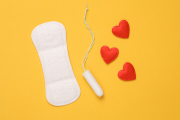 Pad with tampon and hearts on yellow background. Feminine intimate hygiene concept