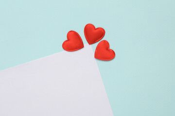 White paper sheet with hearts on blue background. Romantic, love concept, copy space