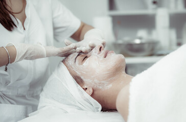 Facial skin care procedures. Beautician makes massage procedure with beauty woman's face in cosmetic clinic
