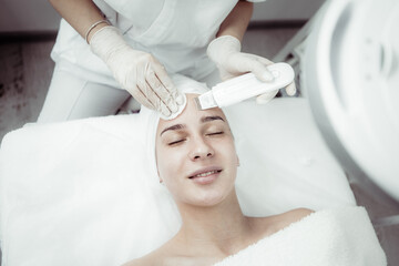 Beautiful woman receiving ultrasonic cavitation facial peeling. Ultrasonic skin cleansing procedure. Cosmetic procedures. Cosmetology. Beauty salon. Skin care.