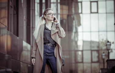 Fototapeta premium Young blonde woman talking on the phone in urban location. Lifestyle