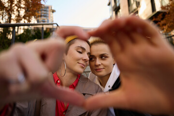 Cute LGBT female couple holding hands in a heart shape