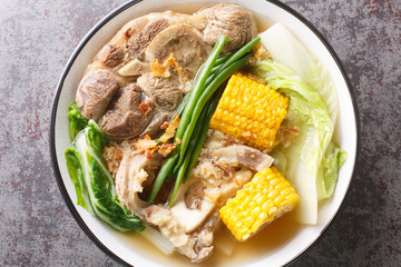 Bulalo is a beef dish from the Philippines soup made by cooking beef shanks and bone marrow with cabbage, corn, scallions, onions, garlic and fish sauce closeup in the bowl. Horizontal top view