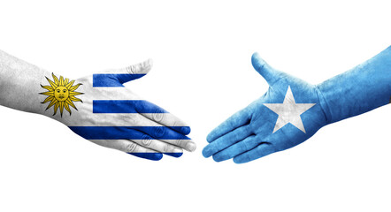 Handshake between Somalia and Uruguay flags painted on hands, isolated transparent image.