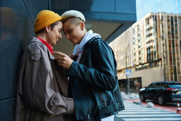 Two young women in love stand against backdrop of cityscape