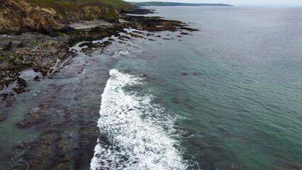 Tidal waves of the Atlantic Ocean. Rocks on the coast of the island of Ireland. White sea foam. Beautiful seaside landscape. Drone photo.