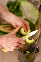 A woman cooking a smoothie from micro-greens and vegetables at home in the kitchen, hands close-up.Healthy eating and healthy lifestyle.Cooking at home. Vegetarian and vegan diet.Veganuary concept.