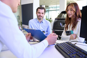 Auto sales consultant showing documentation to automotive buyers