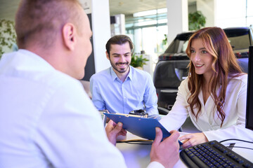 Young woman purchasing new automobile at car dealership