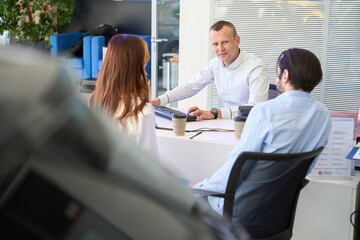 Office manager seated at table communicating with customers