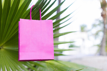 Pink paper bag on a palm leaf, closeup. Mockup.