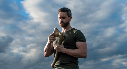 man with axe. lumberjack man hold ax. brutal man on dramatic sky background