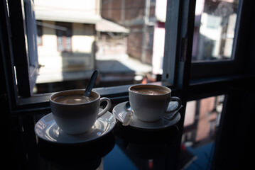 Two cups of coffee kept on a table.