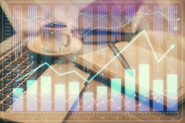 Double exposure of financial chart drawing and desktop with coffee and items on table background. Concept of forex market trading