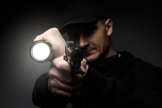 Professional security guard or policeman with flashlight and gun in dark room