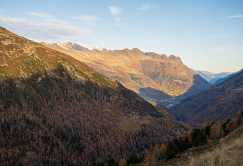 High mountains with rocky peaks partially covered with snow and valleys with coniferous trees.