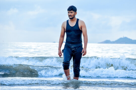 Attractive young Indian guy walking at the beach.