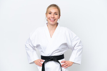 Young caucasian woman doing karate isolated on white background posing with arms at hip and smiling