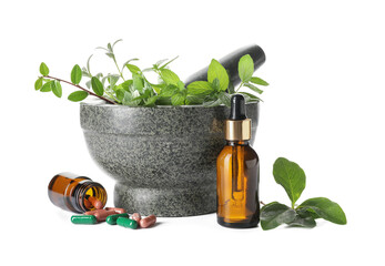 Stone mortar with different herbs, bottle of essential oil and pills on white background