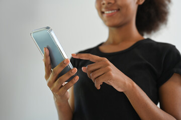 Cropped image of smiling young African American using mobile phone, chatting online, checking social media