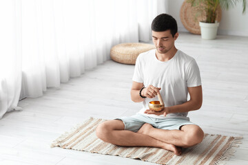 Young man with Tibetan singing bowl meditating at home