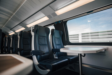 Table and empty seats in modern illuminated passenger intercity train
