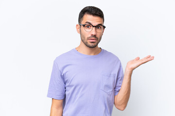 Young caucasian man isolated on white background making doubts gesture