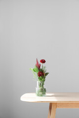 Vase with beautiful ikebana on table near grey wall