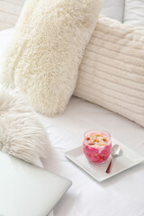 Obraz na płótnie Canvas Glass of tasty yogurt and granola on bed