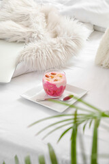 Glass of fresh yogurt with granola on bed