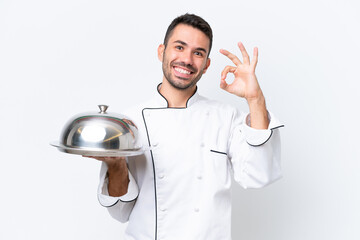 Young chef with tray isolated on white background showing ok sign with fingers - Powered by Adobe