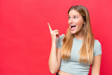 Young beautiful woman isolated on red background intending to realizes the solution while lifting a finger up