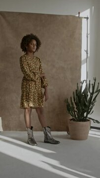 Young black girl afro hair, wearing flowery yellow dress, looking confident 