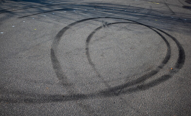 skid marks on a road surface. Circular tire marks left by drivers doing doughnuts - obrazy, fototapety, plakaty