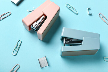 Office staplers, staples and clips on color background