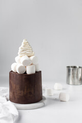 Fototapeta premium marshmallows and meringue on a ganache covered chocolate cake, hot chocolate cake, cake on a marble plate