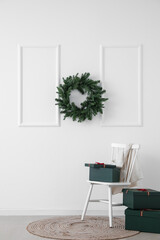 Chair with presents and Christmas wreath hanging on light wall