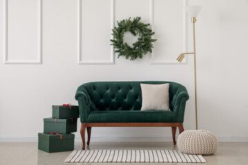 Sofa with presents and Christmas wreath hanging on light wall