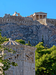 Fototapeta premium The Erechtheion ancient temple on acropolis hill, and scorch of the Wind's Tower in the Roman forum. A beautiful, sunny day in Athens, Greece.