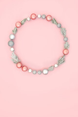 Christmas wreath with winter snow fir and tree bauble ornaments on pastel pink background. Festive abstract minimal design concept for winter Xmas and New Year.
