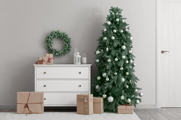 Interior of living room with Christmas tree, mistletoe wreath and chest of drawers